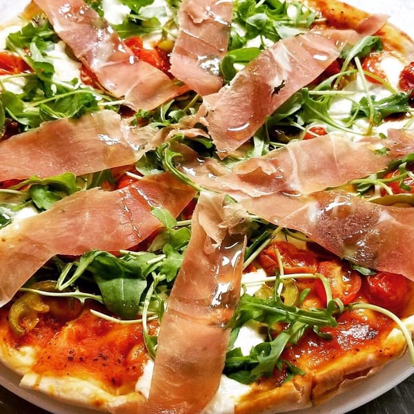 Augie's Italian pizza topped with prosciutto, fresh arugula, cherry tomatoes, and mozzarella.